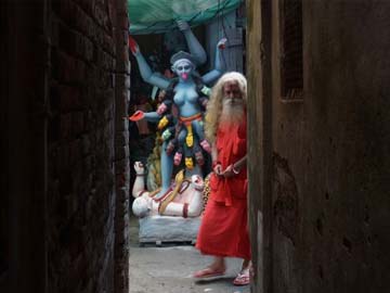 A sadhu walks past a clay idol of Goddess Kali, the goddess of power in Dhami